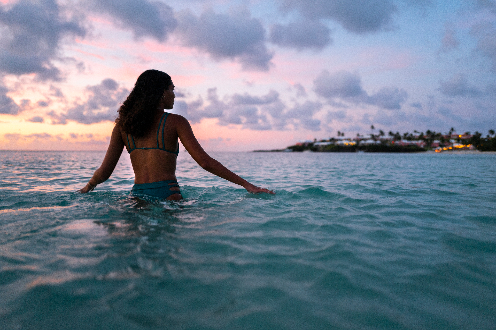 Woman wading in the ocean at sunset in Bermuda